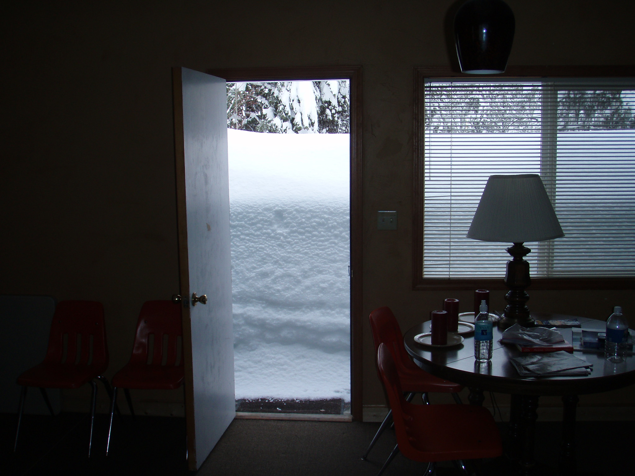 View of snow outside an open front door, taken from inside someones living room.