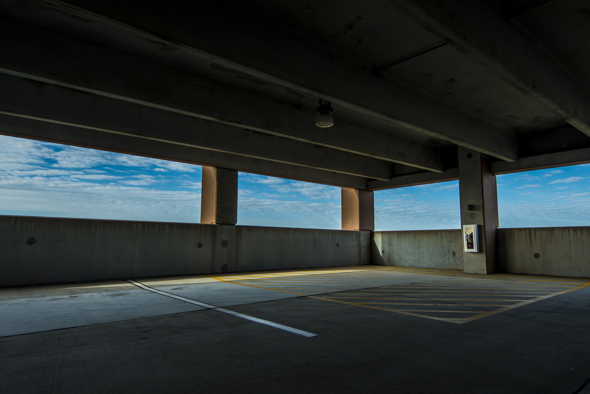 A liminal empty parking garage looking out over a blue sky.